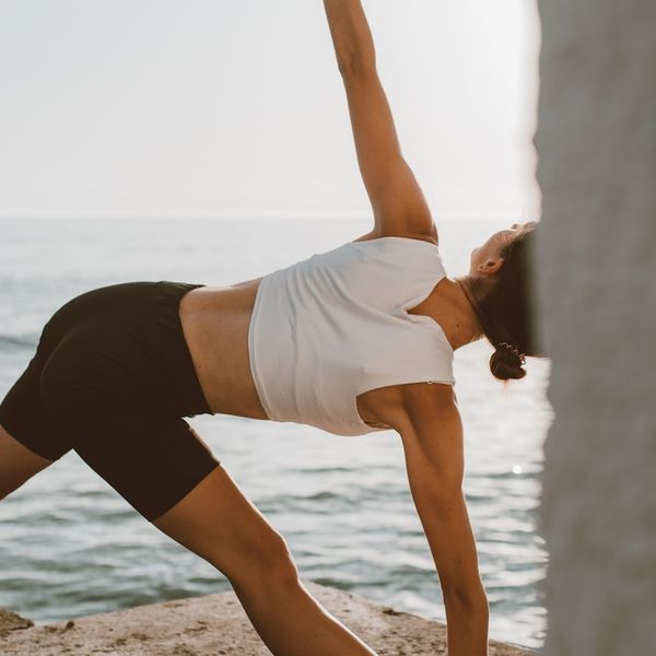 Person feeling energized and stretching arms outdoors at sunrise.